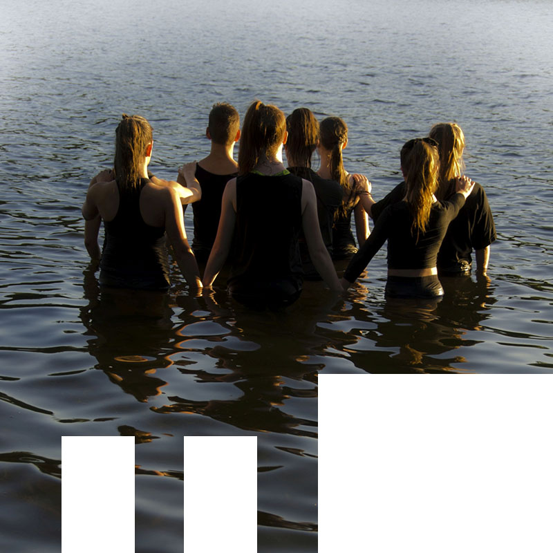 7 people standing in the water with backs to the camera.
