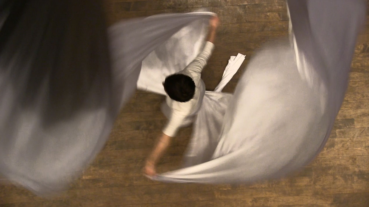A bird's eye view of a person dancing in a long robe.