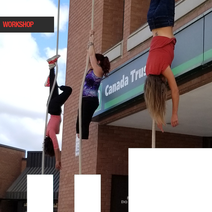 Three female aerial performers hang from the side of Peterborough Square.