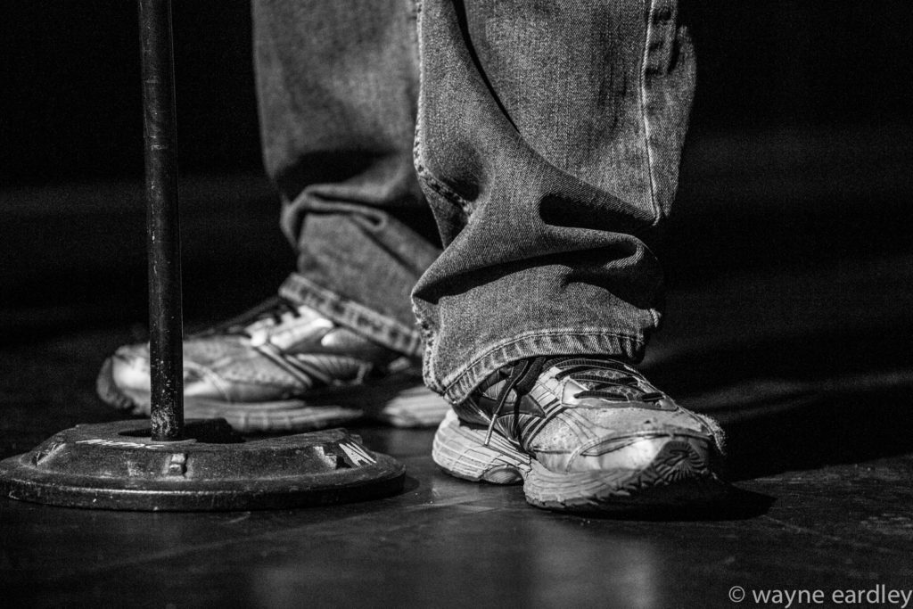 Bill Kimball's sneakers during Public Energy's 25th Anniversary Mainstage event. In greyscale.