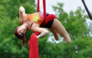 Erin Ball performs outside on red aerial silks.