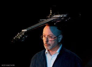 Dancer Ted Robinson balancing an electric guitar on his head.