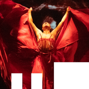 Santee Smith dances, arms raised, wearing a red gauze dress